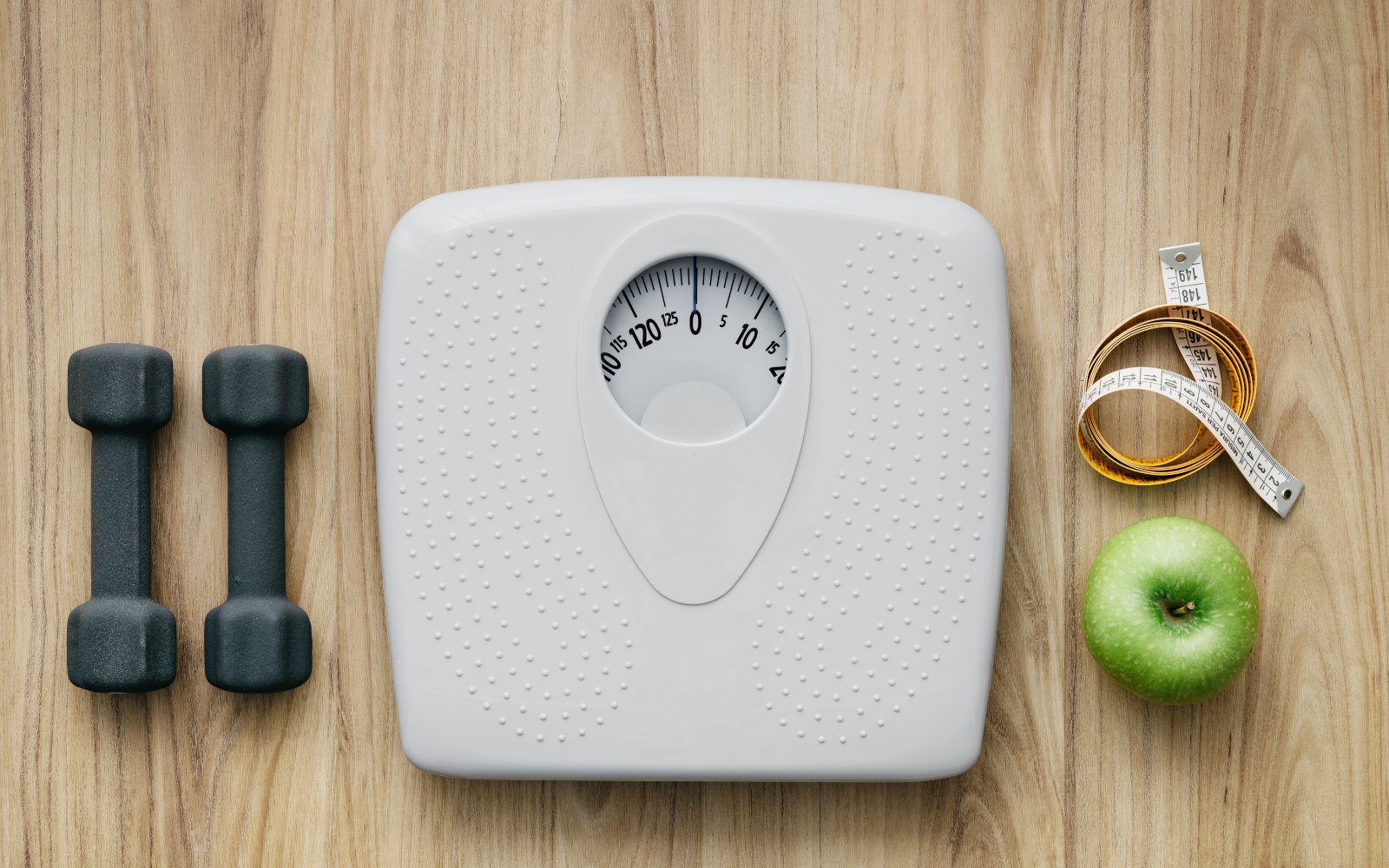 Scale with weights, tape measurer and apple